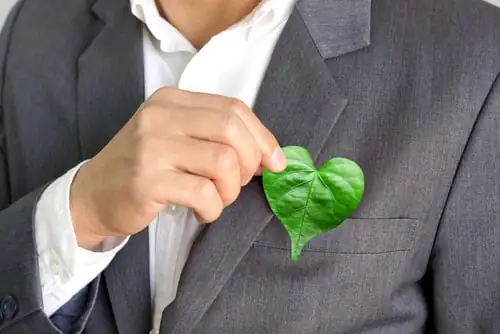 Businessman holding a green heart leaf / Business with corporate social responsibility and environmental concern